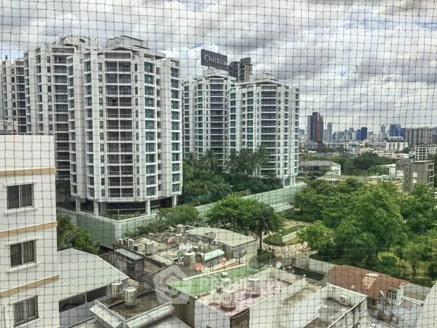 Stunning cityscape view from high-rise apartment with lush greenery and modern buildings.