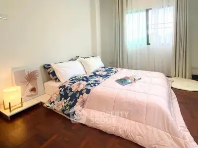 Cozy bedroom with floral bedding and soft lighting, perfect for relaxation and comfort.