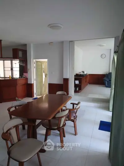 Spacious dining area with wooden furniture and open layout leading to cozy living room.