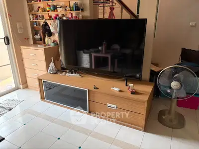 Cozy living room with modern TV stand, fan, and ample storage space, perfect for comfortable living.