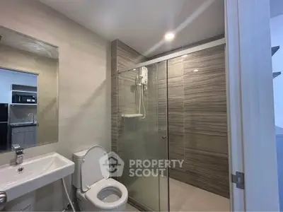 Modern bathroom with glass shower enclosure and sleek fixtures in a contemporary apartment.