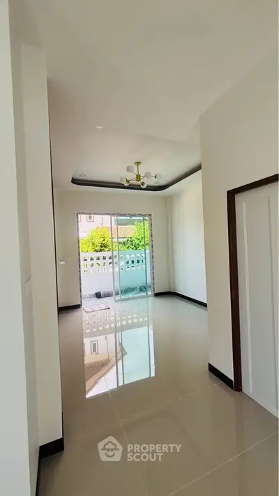 Spacious modern living room with sleek flooring and large windows leading to a balcony.