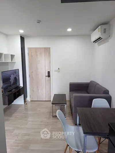 Modern living room with sleek furniture and wall-mounted TV in a cozy apartment.