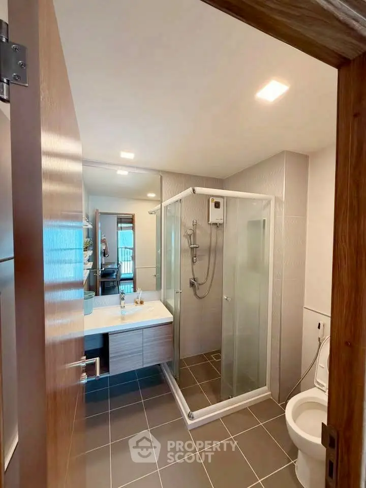 Modern bathroom with glass shower and sleek fixtures in contemporary home.