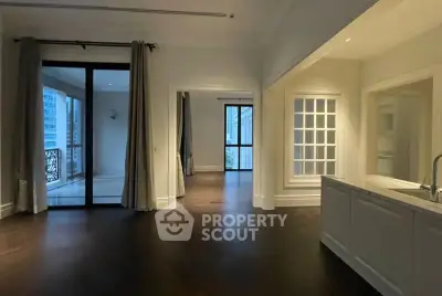 Spacious open-plan living area with elegant dark wood flooring and large windows leading to a balcony.