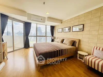 Spacious bedroom with city view and modern decor in high-rise apartment.