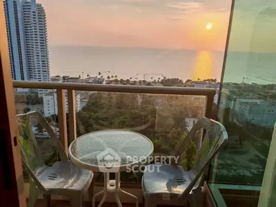 Stunning balcony view of ocean sunset with cozy seating area.