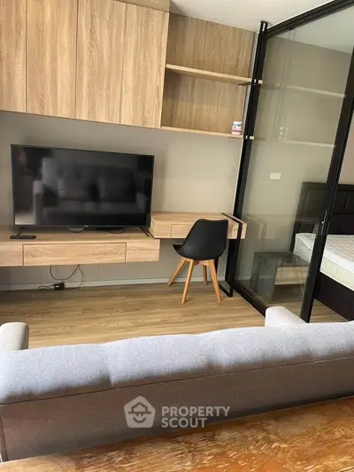 Modern living room with sleek TV setup and stylish wooden furniture, perfect for urban living.