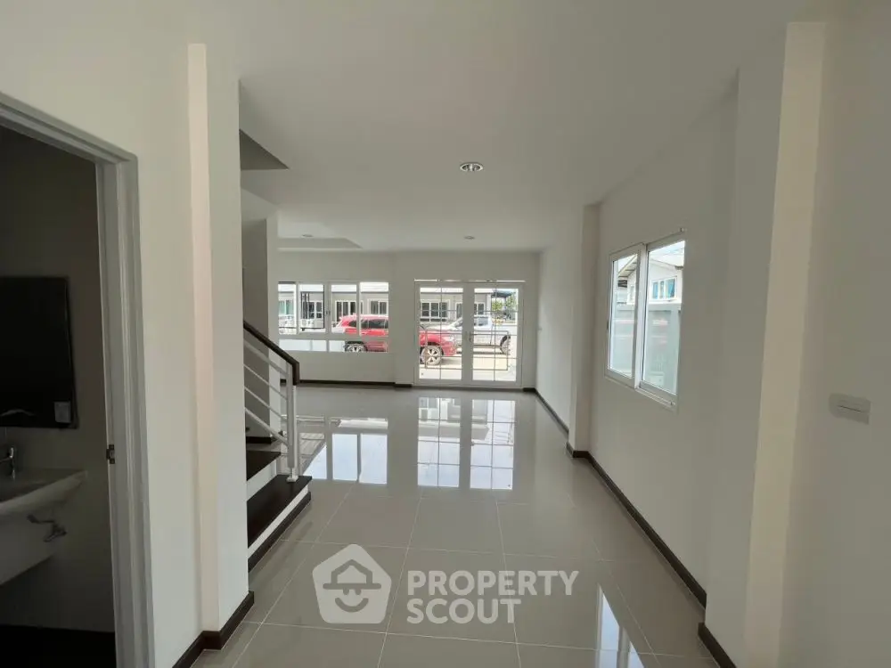 Spacious modern interior with glossy tiled floors and large windows in a bright open layout.