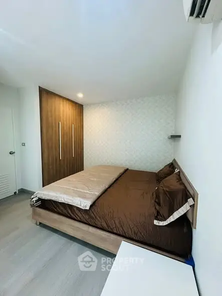 Modern bedroom with stylish wooden wardrobe and cozy bed in a minimalist design.