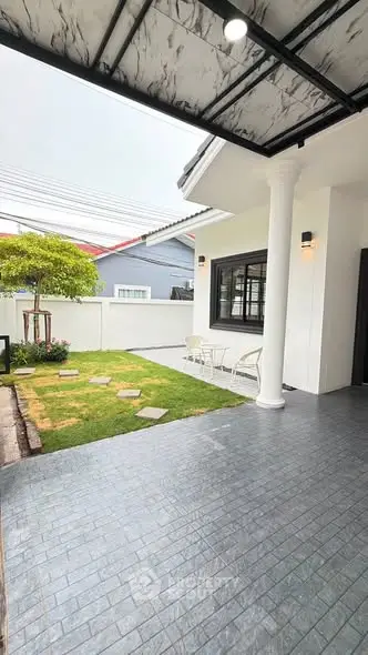 Charming exterior view of a modern home with a cozy patio and lush garden, perfect for relaxation.