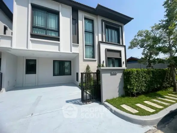 Modern two-story house with sleek design and lush greenery in a serene neighborhood.