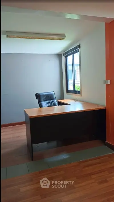 Modern office space with sleek desk and ergonomic chair, featuring large window for natural light.
