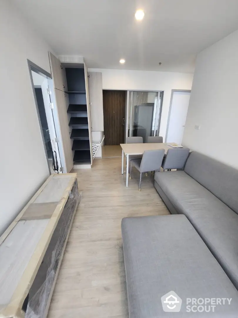 Modern living room with sleek furniture and built-in shelving, featuring a cozy gray sofa and dining area.