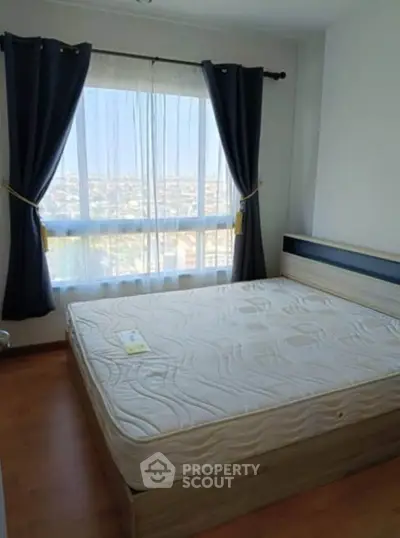 Bright bedroom with large window and city view, featuring a comfortable bed and elegant curtains.