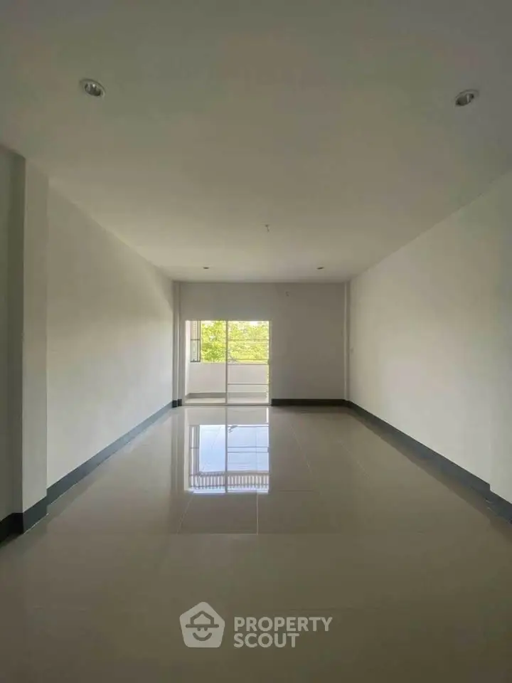 Spacious empty room with glossy tiled floor and large window view