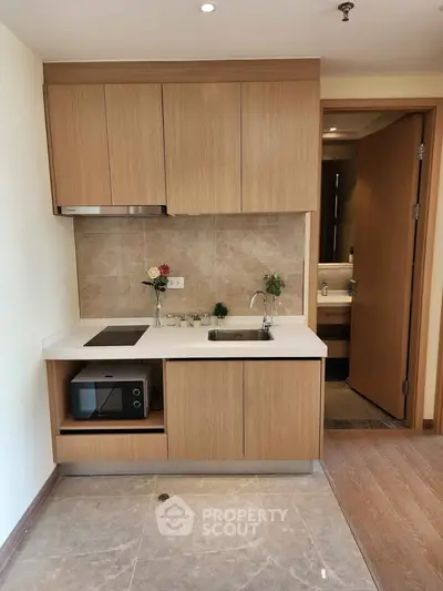 Modern compact kitchen with wooden cabinets and built-in microwave