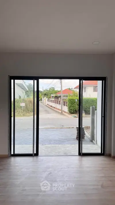 Spacious room with sliding glass doors opening to a suburban street view, ideal for natural light and ventilation.