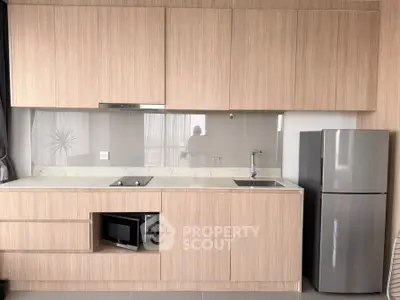 Modern kitchen with sleek cabinetry and stainless steel fridge in a stylish apartment.