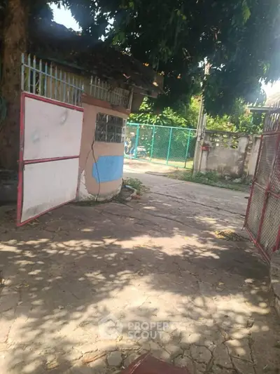 Charming gated entrance with lush greenery and paved pathway