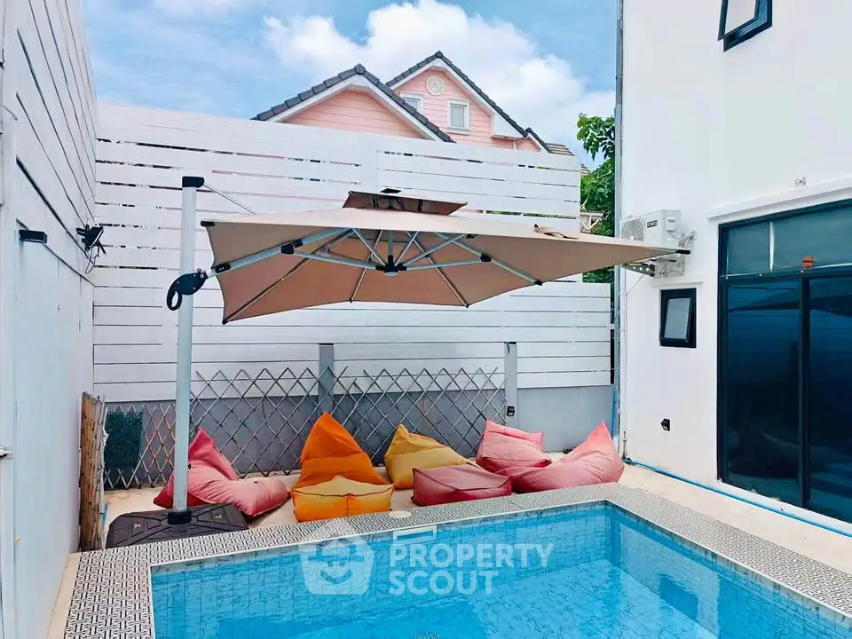 Charming poolside retreat with cozy seating and modern umbrella, perfect for relaxation and entertainment.