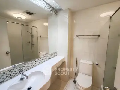 Modern bathroom with sleek fixtures and large mirror, featuring a spacious shower area.