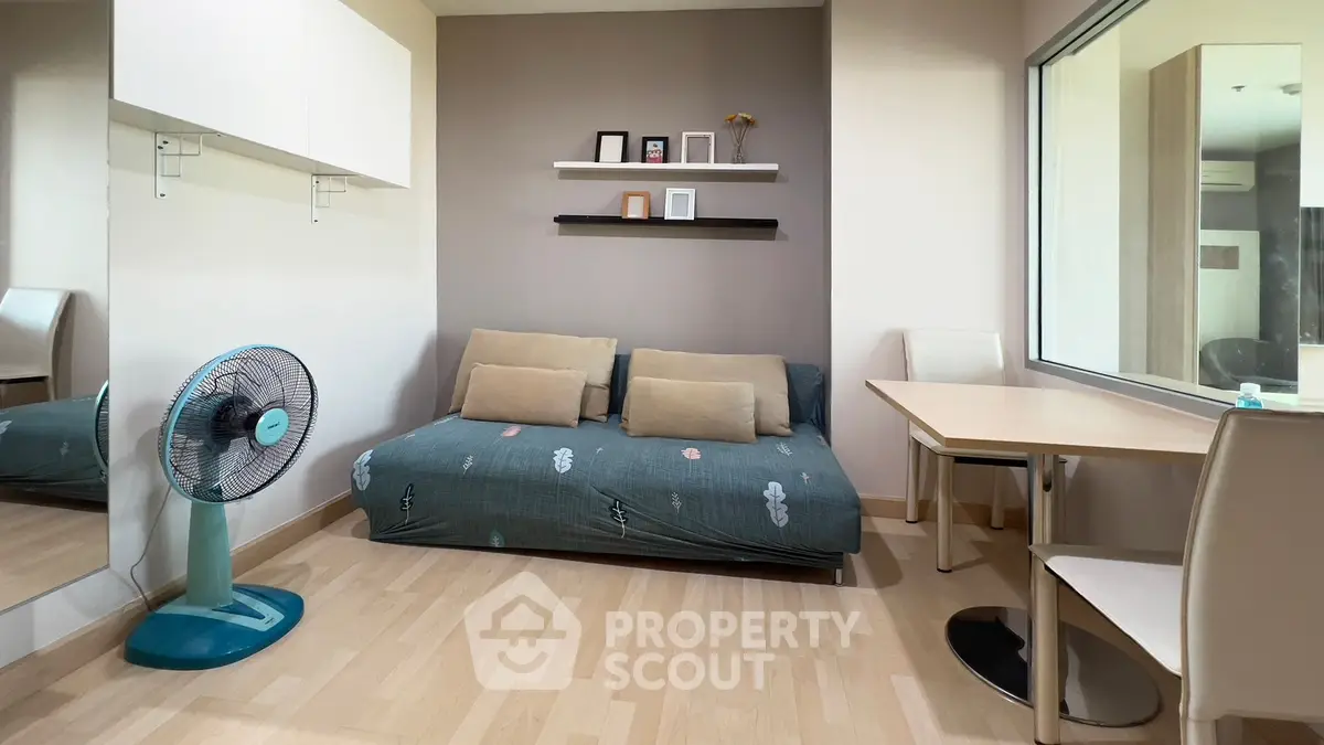 Cozy living room with modern decor, featuring a stylish sofa, wall shelves, and a sleek fan for comfort.