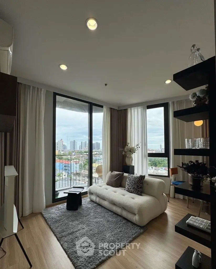Modern living room with large windows and city view, featuring stylish decor and cozy seating area.