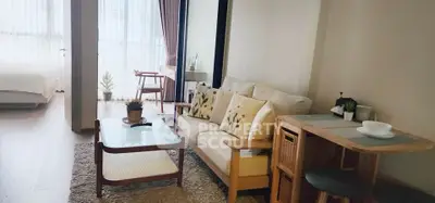 Cozy living room with natural light and modern decor, adjacent to a bright bedroom.