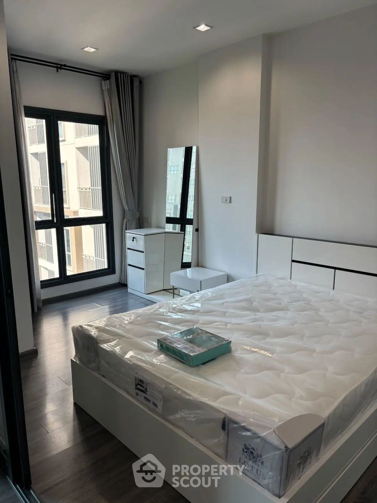 Modern bedroom with large window and stylish furniture in a contemporary apartment.