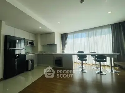 Modern kitchen with sleek design, open layout, and stylish bar seating in a bright apartment.