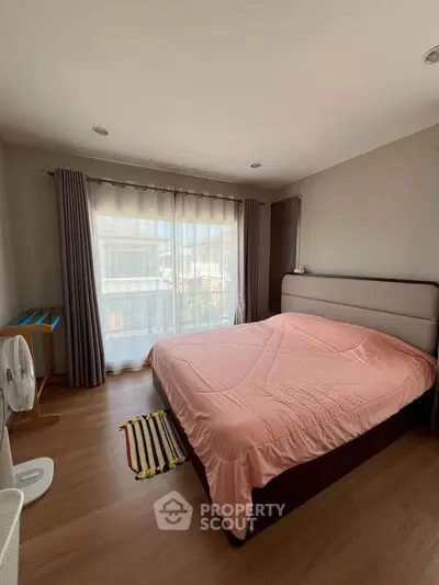 Spacious bedroom with large window and pink bedding in modern apartment