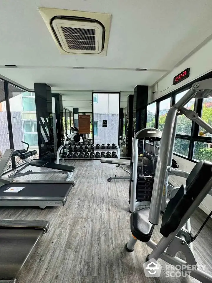 Modern gym with state-of-the-art equipment and large windows in a residential building.