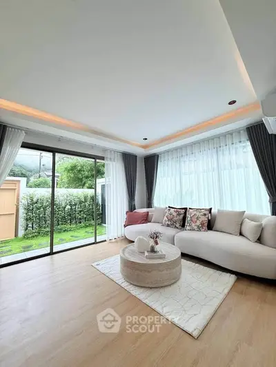 Elegant living room with modern decor and large windows overlooking a lush garden, perfect for relaxation.