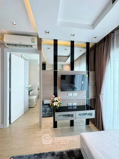 Modern living room with sleek design, featuring a wall-mounted TV, air conditioning, and elegant decor.