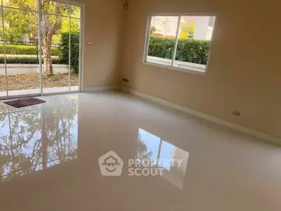 Spacious living room with glossy floors and large windows offering garden views.