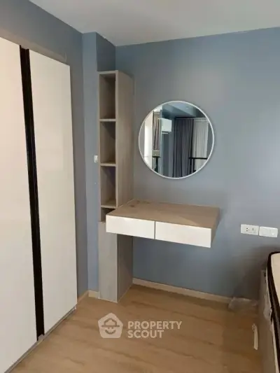 Modern bedroom with sleek wardrobe and stylish vanity mirror.