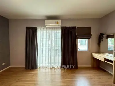 Spacious bedroom with large window and elegant wooden flooring