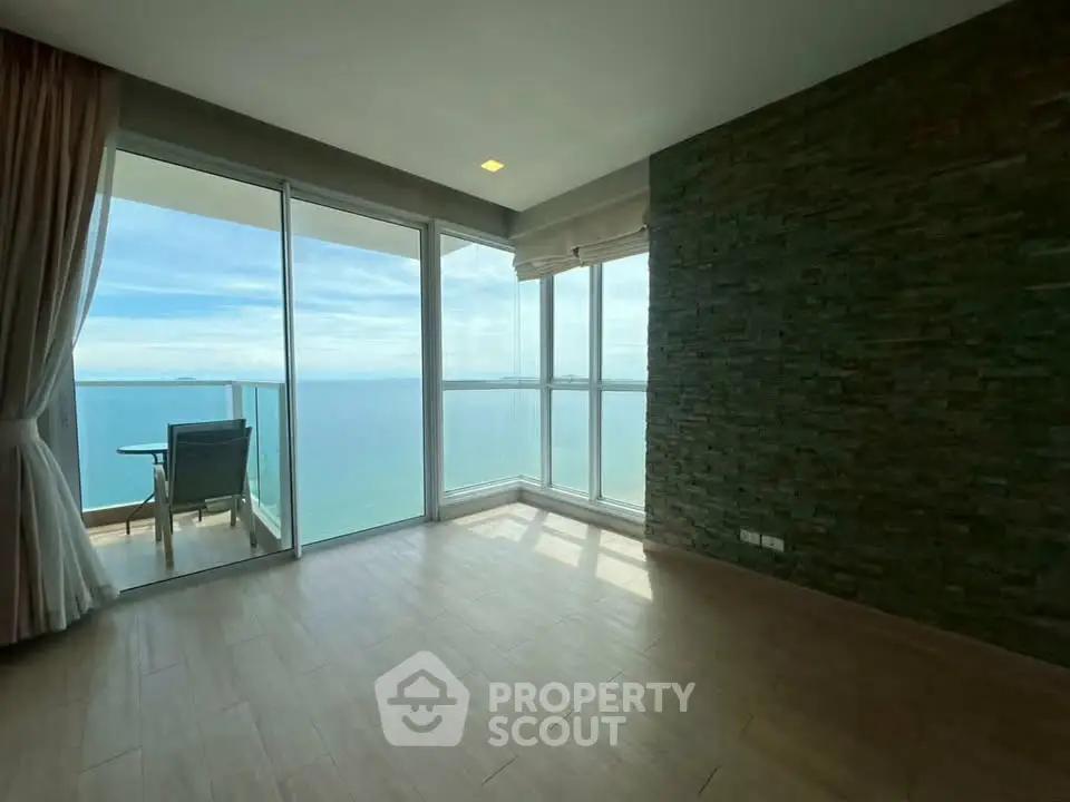 Stunning ocean view from modern living room with floor-to-ceiling windows and balcony access.