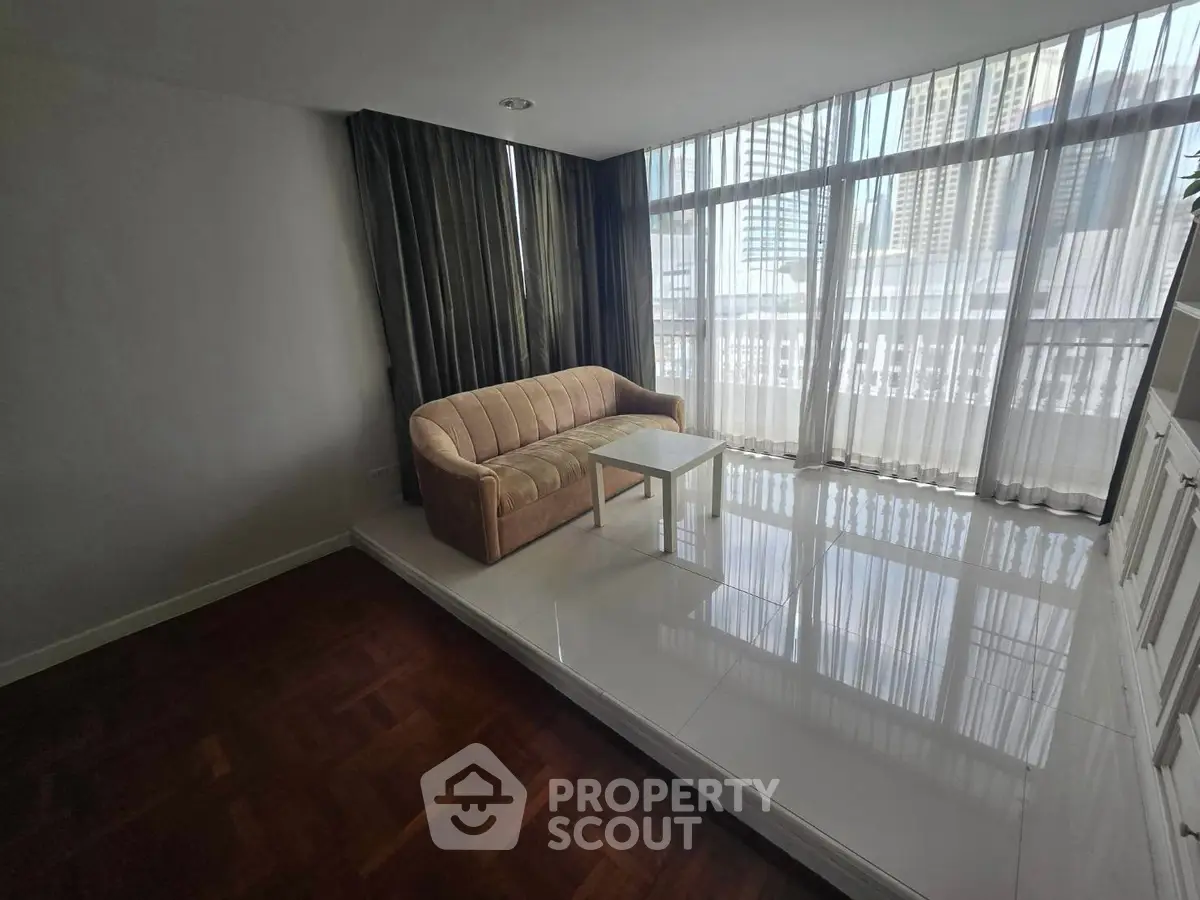 Spacious living room with large windows and city view, featuring a cozy sofa and elegant flooring.