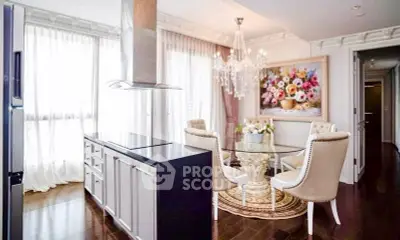 Luxurious dining area with elegant chandelier and modern kitchen island in upscale apartment.