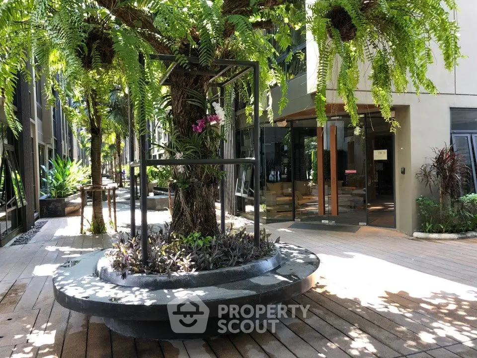 Modern apartment complex entrance with lush greenery and stylish design