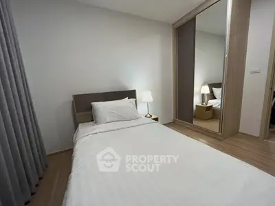 Modern bedroom with sleek design and mirrored wardrobe in a cozy apartment.