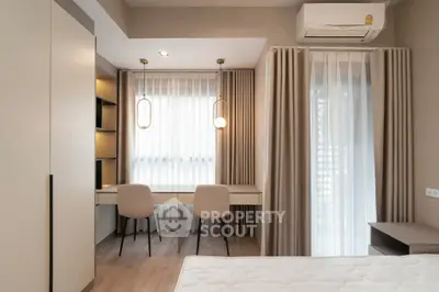 Modern bedroom with study area, featuring elegant lighting and neutral decor.
