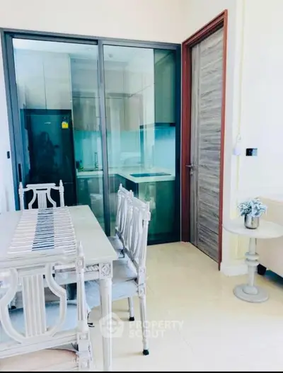 Elegant dining area with glass partition and modern kitchen view