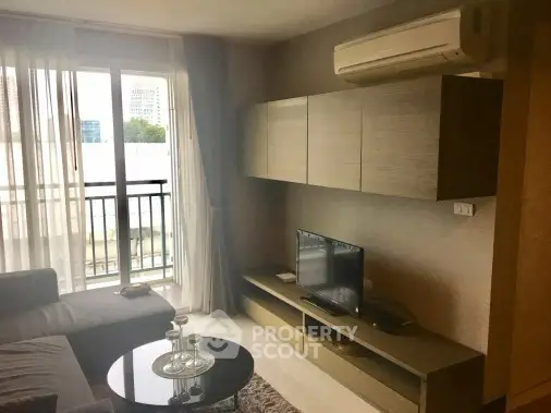 Modern living room with balcony view, featuring sleek furniture and air conditioning.