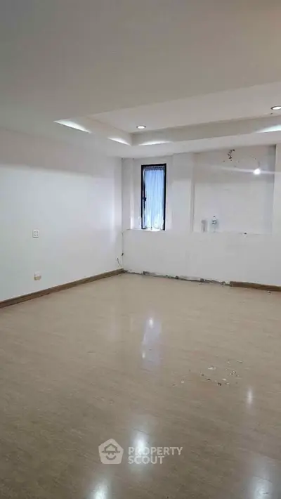 Spacious empty room with wooden flooring and recessed lighting, ideal for customization.