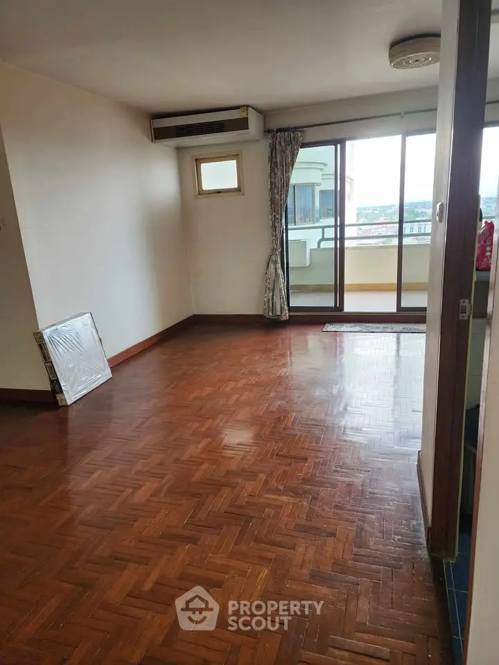 Spacious living room with parquet flooring and balcony access