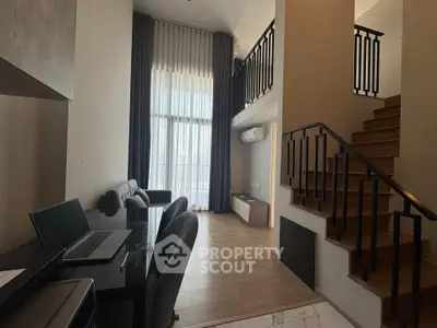 Modern duplex apartment with high ceilings and stylish staircase, featuring a cozy workspace and large windows.