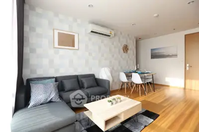 Modern living room with stylish decor and dining area, featuring wooden flooring and natural light.